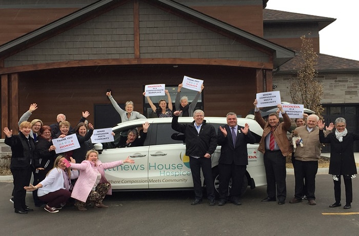 A group of Matthews House Hospice volunteers pose by a brand new Honda Odyssey